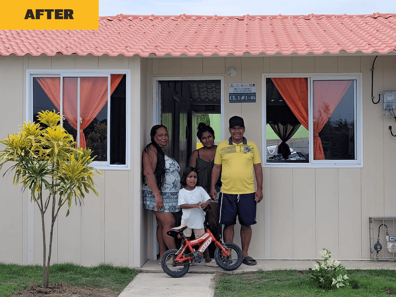Family standing in front of renovated home with new roof showing Equifruit Fairtrade farmer impact and community uplift